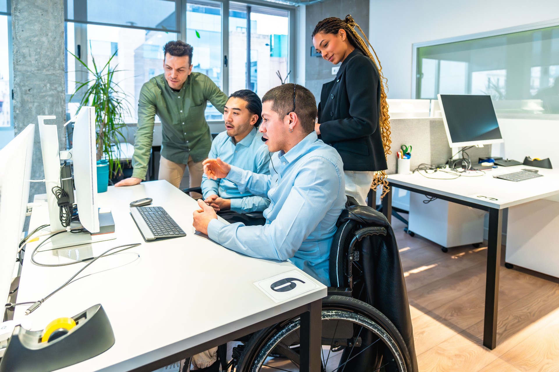 Diverse business team collaborating on computer project in modern office