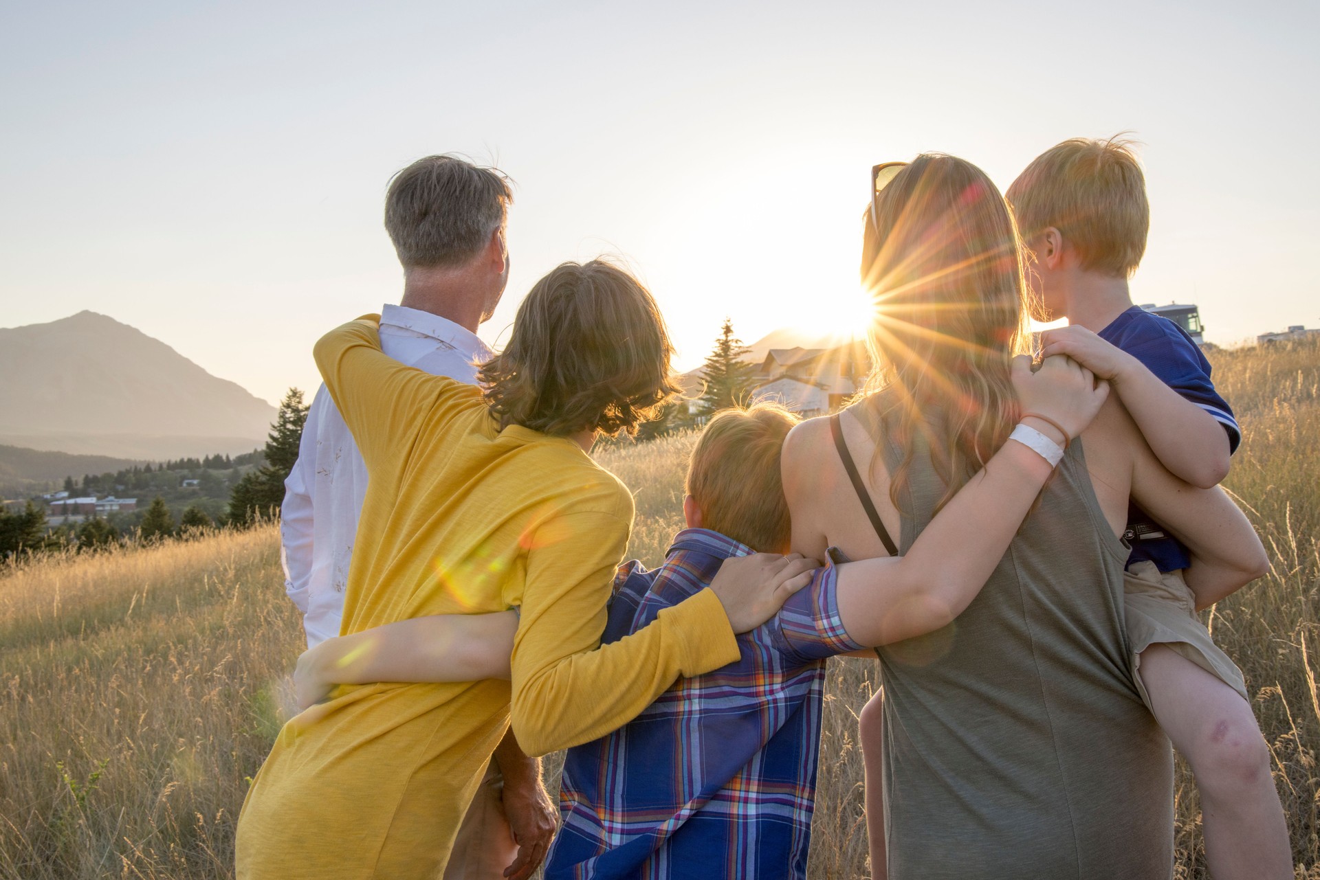 Young family in mountain meadow at sunset